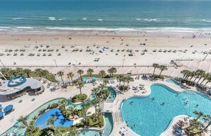 Un resort con una playa extensa, varias piscinas y palmeras.