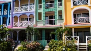 Una hilera de edificios coloridos con balcones, un paseo empedrado y un muelle que se adentra en el agua.