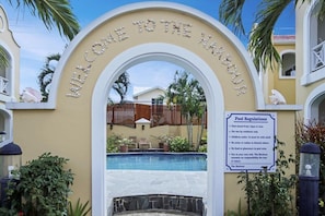 A pool area with a sign reading "Welcome to the Harbour" and "Pool Regulations" listing rules like pool hours and use by residents only. - Marina-view 3BR condo in Rodney Bay with pool, AC & WiFi, Harbour#7 (Rodney Bay)