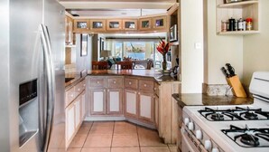 Cocina compacta con refrigerador, estufa, armarios de madera y comedor con vista.
