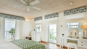 A bedroom with a bed, dresser, vanity, and a balcony. - Beautiful 2-bed cliffside villa - Saline Reef (Cap Estate)