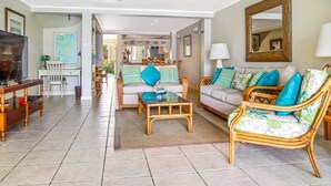 A spacious living room with wicker furniture, a television, and a dining area in the background. - 2 Bedroom townhouse ideally located in Rodney Bay - Harbour #7 (Rodney Bay)