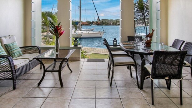 A patio with a glass table and chairs, a view of a marina with boats, and a tropical plant arrangement. - 2 Bedroom townhouse ideally located in Rodney Bay - Harbour #7 (Rodney Bay)