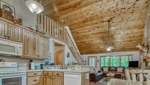 A spacious kitchen with wooden cabinets, a central island, and a dining area with a large table. - Relaxing Helen, Ga Cabin Min from Helen, Sleeps 12 with Hot Tub & Firepit! 
     (Sautee Nacoochee)
