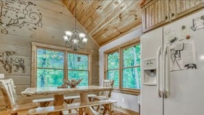 A rustic cabin interior with a wooden dining table, chairs, a chandelier, and a refrigerator with notes. - Relaxing Helen, Ga Cabin Min from Helen, Sleeps 12 with Hot Tub & Firepit! 
     (Sautee Nacoochee)