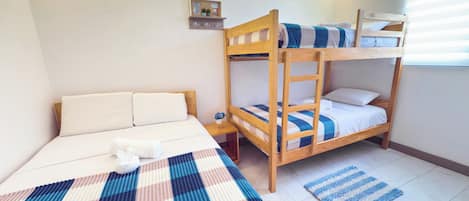 A room with a bunk bed, a single bed, and a small bedside table.