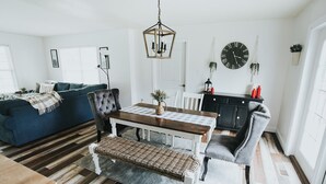 Ett modernt vardagsrum med en matplats, med ett träbord, en blå soffa och en kristallkrona.