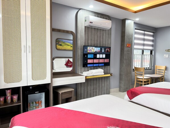 Habitación de hotel con cama, televisión, aire acondicionado, refrigerador pequeño y ventana con persianas.