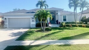 A single-story house with a garage, a front porch, and a well-maintained lawn. - RENOVATED HOUSE-NEW HEATED POOL-HOT TUB-CLOSE TO BEACH- MACKLE PARK-BEACH GEAR (Marco Island)