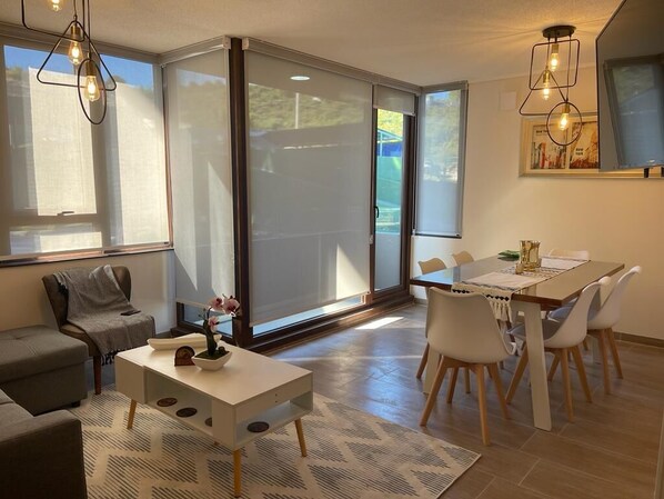 Uma sala de estar moderna com um sofá, uma mesa de centro e uma área de jantar com mesa e cadeiras.