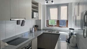 Une cuisine moderne dotée d’un plan de travail en granit, d’un four encastré et d’une fenêtre offrant une vue agréable.