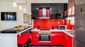 Une cuisine moderne avec des meubles de couleur rouge, des appareils en acier inoxydable et un îlot central doté de sièges.