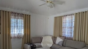 A living room with a sofa, ottoman, and a ceiling fan.