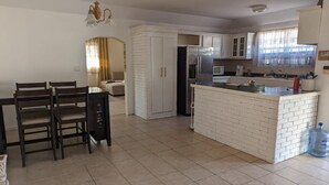 A modern kitchen with white cabinets, a central island, and a dining area with a table and chairs.