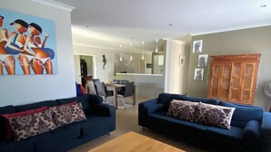 Ein Wohnzimmer mit zwei Sofas, einem Holztisch und einem Essbereich im Hintergrund.