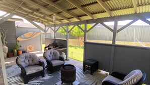 Eine Terrasse im Freien mit Korbmöbeln, einem Grill und einem dekorativen Teppich.