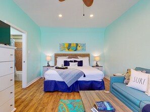 A bedroom with a bed, bedside tables, a dresser, a sofa, and a rug. - Walk to Sandfest , Shared Pool, Board Walk to Beach (Port Aransas)