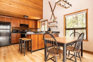 Eine moderne Küche mit Holzschränken, einem Edelstahlkühlschrank und einer zentralen Kochinsel mit Barhocker.