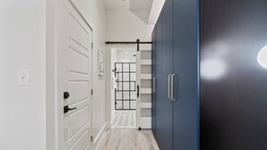Ein Flur mit weißen Türen, einem blauen Kleiderschrank und einem gefliesten Boden.