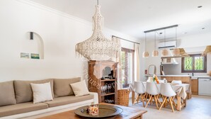 A modern living room with a wooden coffee table, a beige sofa, and a dining area with white chairs. - CostaBlancaDreams - Casa Leo in Benissa Costa (Benissa)