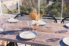 Enjoy a casual yet elegant outdoor dining experience with a beautifully set table amidst the surrounding landscape.