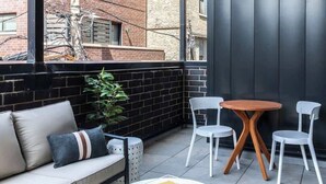 Un espace de détente extérieur moderne, comprenant un canapé, deux fauteuils, une petite table ronde et une plante en pot.