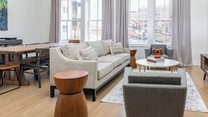 Un salon moderne comprenant un canapé, des fauteuils, une table basse et un coin repas avec des chaises et une table.