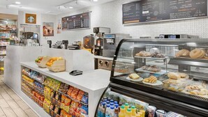 Ein Bäckereiteil mit einer Auswahl an Backwaren, eine Kühlvitrine für Getränke und eine Theke mit Snacks und einem Bezahlsystem.