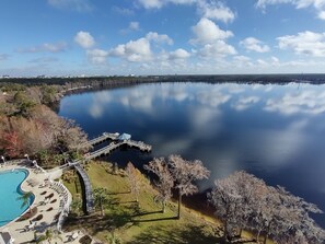 A lakeside resort with a swimming pool, a dock, and a bridge connecting to the water.