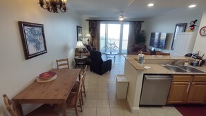 A modern kitchen with a dining area, a ceiling fan, and a view to the outside.
