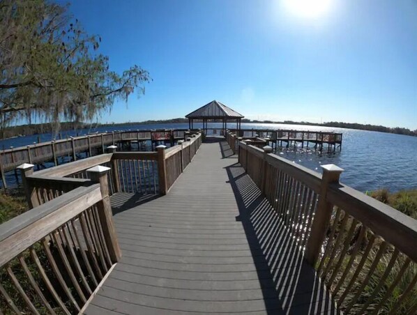 A wooden pier leading to a gazebo by a calm lake.