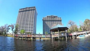 A waterfront view with two high-rise buildings and a wooden gazebo.