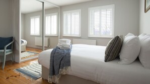 Une chambre à coucher avec un lit, une chaise, un miroir et une fenêtre.
