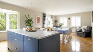 Un vaste espace de vie comprenant un grand îlot de cuisine, une table à manger et un coin salon.