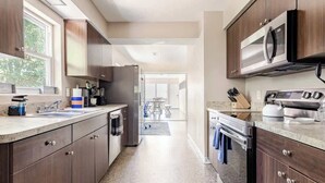 Une cuisine moderne avec des meubles en bois foncé, des appareils électroménagers en acier inoxydable et une grande fenêtre qui laisse entrer la lumière naturelle.