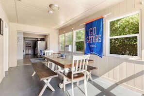 Un comedor con una mesa y sillas de madera, una cocina al fondo y un cartel con la leyenda "GO GATORS" en la pared.