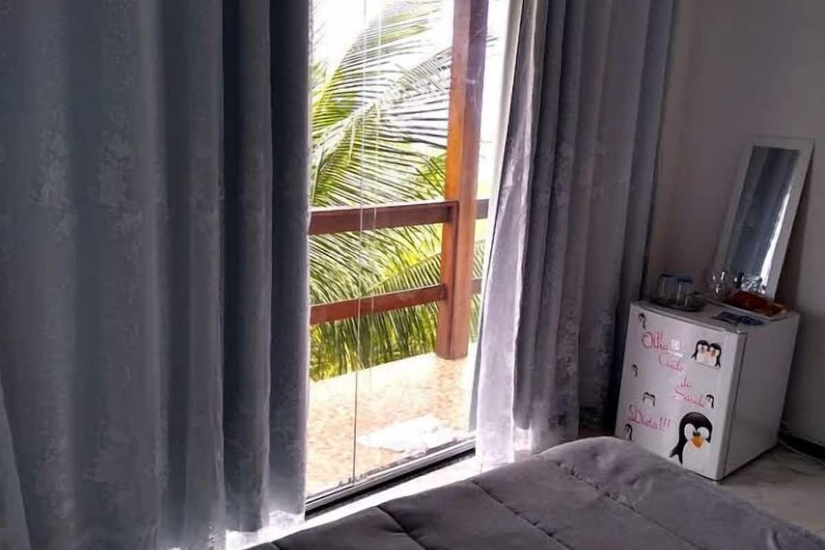 A room with a large window, a wooden balcony, and a white cabinet with decorative penguin stickers.