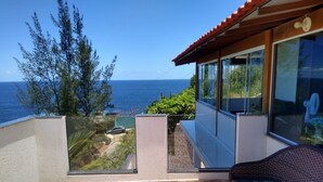 A balcony with a view of the sea, a wicker table, and a sofa. - Farol House (Marica)