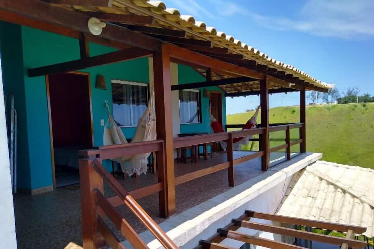 A wooden porch with a hammock and a view of a green field.