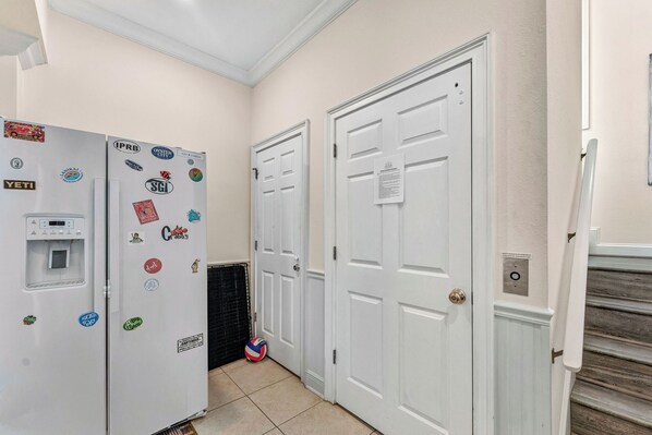 A hallway with two white doors, a refrigerator with various magnets, and a water dispenser.