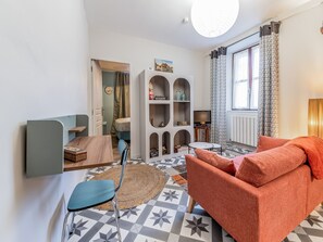 Relax in this inviting living room with a comfortable sofa, chair, and TV on a wooden stand.
