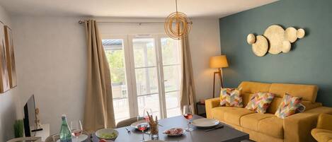 Un coin repas avec une table dressée pour deux personnes, un canapé et une lampe.