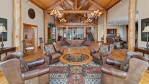 A spacious living area with a high wooden ceiling, leather sofas, a central coffee table, and a patterned rug. - Escape the Heat in the High Country - 3 King Bedrooms & Amazing Views! (Banner Elk)
