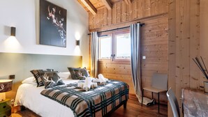 A wooden cabin-style bedroom with a bed, bedside lamps, a window with curtains, and a chair. - Duplex Aravis - Welkeys (Praz-sur-Arly)