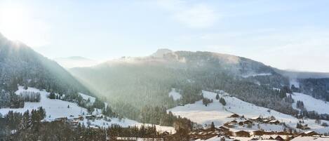 A mountain resort with wooden buildings, snow-covered slopes, and a clear sky.