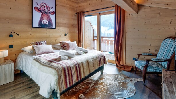 A wooden cabin bedroom with a bed, a chair, and a large window. - Duplex Aravis - Welkeys (Praz-sur-Arly)