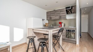 A modern kitchen with a wooden table and bar stools, a coffee maker, and a built-in oven.