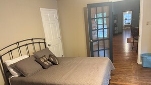 Un dormitorio con cama, una puerta y un pasillo que conduce a otra habitación.