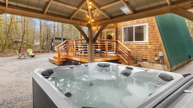 Un espace dédié à un bain à remous, doté d’une terrasse en bois et d’une structure couverte.