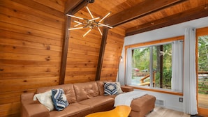 Une pièce chaleureuse avec un canapé en cuir marron, un fauteuil jaune et un tapis coloré.
